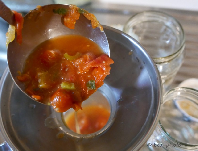 Heiße Tomatensauce wird in vorbereitete Gläser gefüllt.